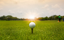 Golf Ball On Tee Ready To Shot On Blurred Landscape Of Green Course With Sunlight On Background.