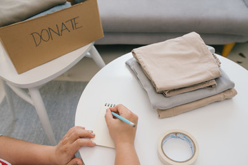 Wall Mural - Volunteer writing in notebook and near carton box with clothes