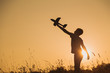 © Andrii Oleksiienko - Black silhouette of young caucasian kid isolated on sunny golden sunset sky background. Boy playing toy plane outside on grassy summer hill. Setting big goals and dreaming about happy future concept.