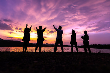 Silhouette of friends enjoy while dramatic sunset sky with beautiful clouds. Traveling and vacation concept.