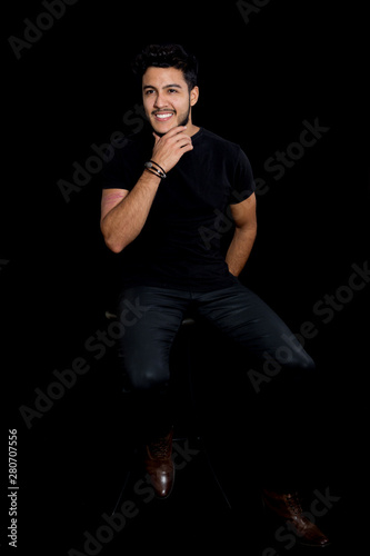 Young Latin Man Poses In A Studio For A Low Key Portraits He Is Sitting On A Stool Stock Photo Adobe Stock