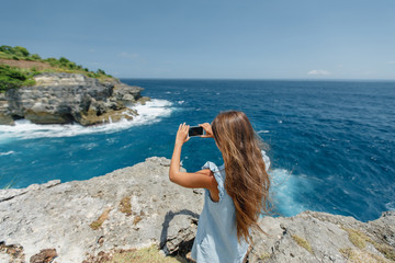 young woman on the beach taking picture on her phone