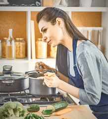 Wall Mural - Beautiful girl is tasting food and smiling while cooking in kit