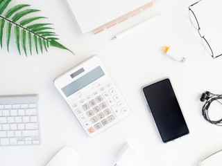 Poster - top view of office desk table with  calculator, notebook, plastic plant, smartphone and keyboard on white background, graphic designer, Creative Designer concept.
