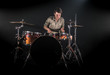 © puhimec - Professional drummer playing on drum set on stage on the black background