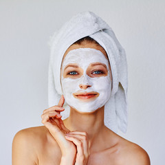 Beautiful woman applying facial mask on her face. Skin care and treatment, spa, natural beauty and cosmetology concept.