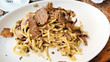 Italian pasta with shaved truffle in a mushroom sauce. Close up view on a white plate.