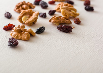 Wall Mural - A variety of peeled walnuts and raisins on a white wooden background. View from above. Plenty of space for text.