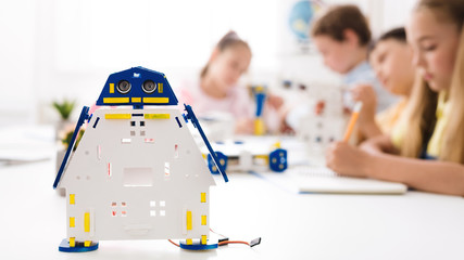 Wall Mural - Handmade robot at desk with schoolchildren at background