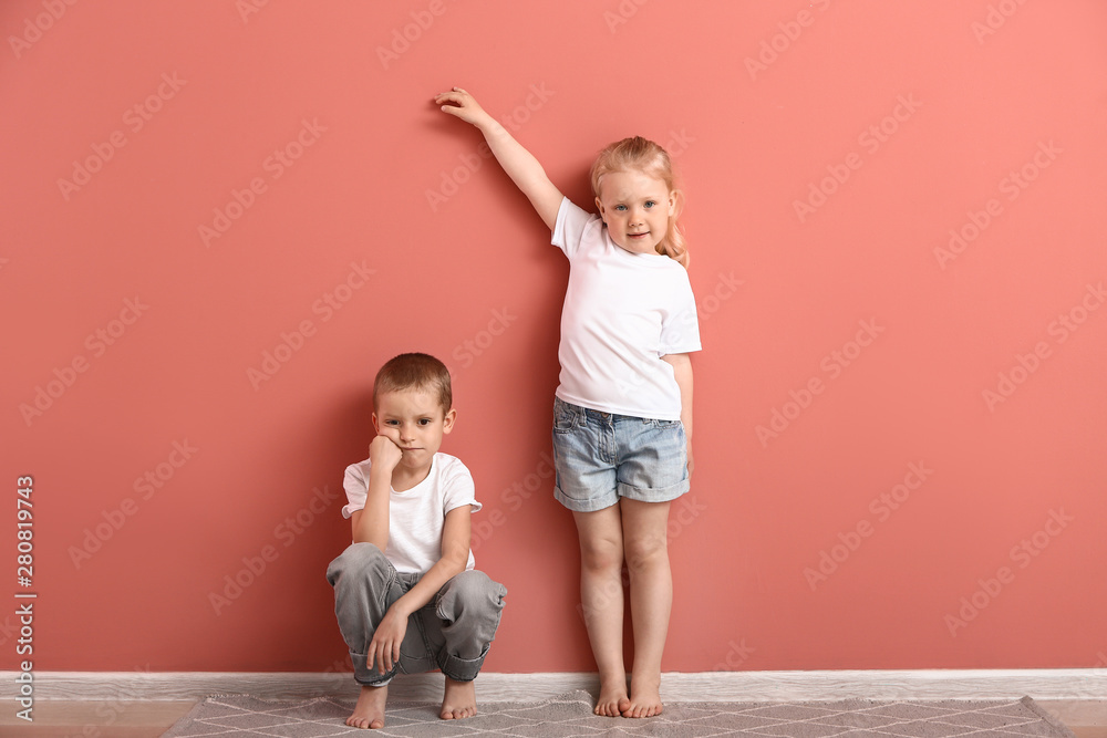 Little children measuring height near wall