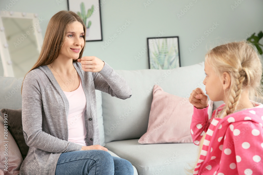 Mother teaching her deaf mute daughter to use sign language at home