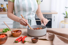 Woman Cooking Traditional Chili Con Carne In Kitchen
