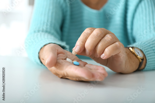 Fotografía Elderly woman with pills at white table, closeup