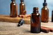 Bottle of essential oil and cinnamon sticks on wooden table against blue background. Space for text