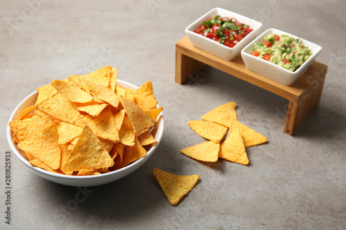 Cuadros en Lienzo Bowl of delicious mexican nachos chips served with sauces on grey table
