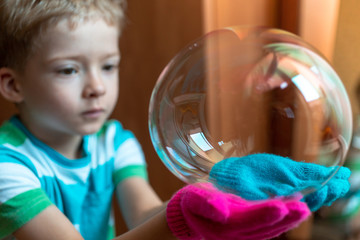 boy playing with a soap bubble. gloves for playing with soap bubbles. big bubble