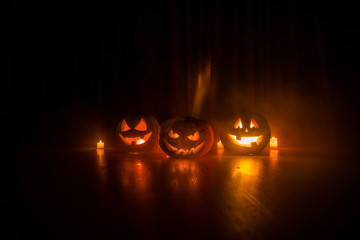 Halloween pumpkin head jack o lantern with glowing candles on background. Pumpkins on wooden floor