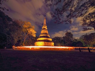 In Buddhist holy day people walk with lighted candles in hand around the pagoda .