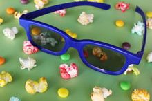 3D Glasses For Watching Movie And Colored Popcorn On Green Background.