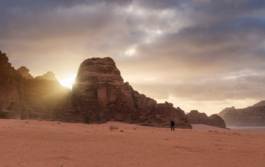 Wall Mural - wadi rum desert landscape in sunrise. a man walking alone in wadi rum desert in jordan, middle-east