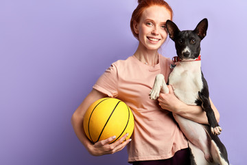 Wall Mural - cheeful positive girl having fun with a pet. close up portrait, isolated blue background, studio shot. joy concept