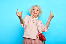 Elder Cheerful Positive Gorgeous Lady Making Rock Sign, Isolated Blue Background, Studio Shot. Body Language, Lifestyle, Free Time, Spare Time