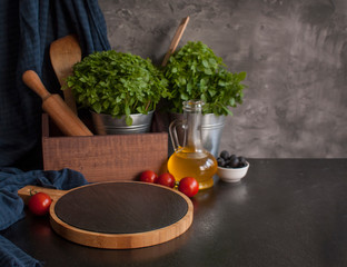 An empty wooden cutting Board on the table with vegetables, olive oil and herbs. Free space for objects. Copy space