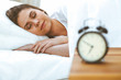 © rogerphoto - Beautiful young and happy woman sleeping while lying in bed comfortably and blissfully smiling