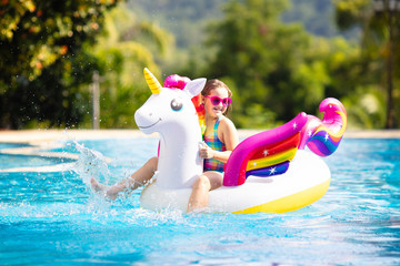 Wall Mural - Child on unicorn float in swimming pool. Kids swim