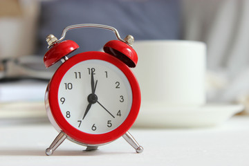 Alarm clock and cup of coffee in the room interior