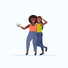 Wall Mural - thin and fat girls taking selfie photo on smartphone camera african american smiling women couple standing together flat full length white background