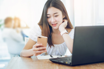 Portrait of young asian woman using smartphone and laptop working n cafe