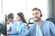 © ty - Portrait of call center worker accompanied by his team. Smiling customer support operator at work.