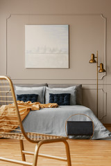 Stylish golden lamp next to king size bed with blue bedding and dark blue pillows