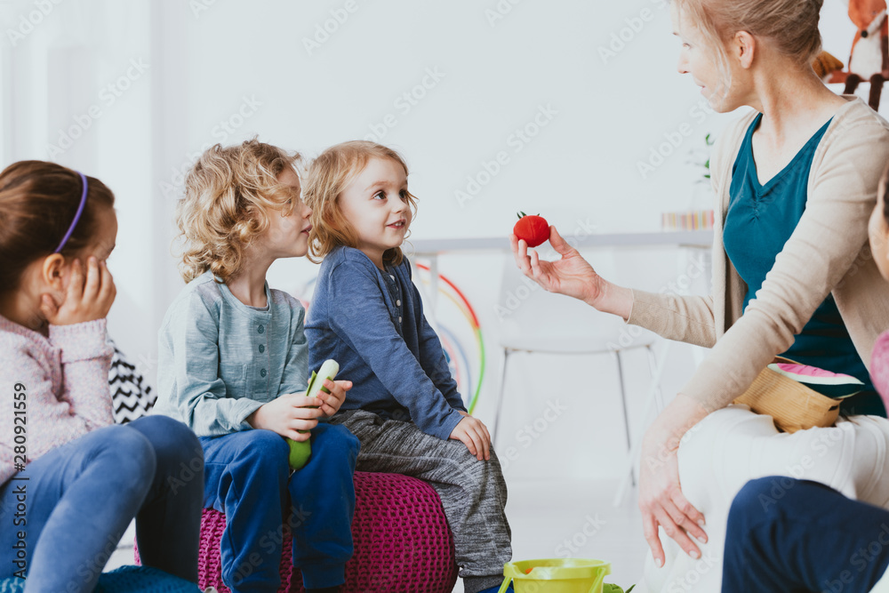 Two cute boys and little girl learning english with teacher in preschool - obrazy, fototapety, plakaty 