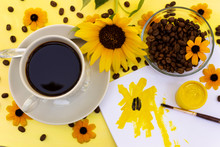A Cup Of Coffee, Coffee Beans, Yellow Flowers, A Flower Of A Sunflower And A Sketch-blob On A Yellow Background Is The Concept Of Warm Yellow Summer Energy Of Coffee Drink And Summer Creativity.