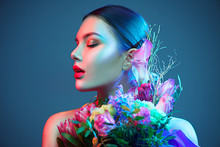 Sexy Brunette Model Girl With Bouquet Of Beautiful Flowers. Beauty Young Woman With Bunch Of Flowers In Colorful Neon Lights. Art Design