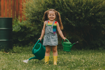 Little girl with watering cans in the garden.