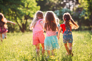 Wall Mural - Large group of kids, friends boys and girls running in the park on sunny summer day in casual clothes .