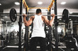 © Gayan - Man at the gym. Execute exercise squatting with weight, in gym