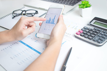 Poster - Close-up pictures of businessmen using smartphones. Calculate financial graphs on a white table.