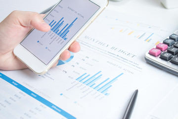 Poster - Smart phone screen shows a graph of the financial business desk white.