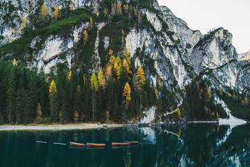 Autumn landscape of Lago di Braies Lake in italian Dolomites mountains in northern Italy. Drone aerial photo with Wooden boats and beautiful reflection in calm water at sunrise. Pragser Wildsee