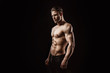 © KDdesignphoto - Muscular model sports young man on dark background. Fashion portrait of strong brutal guy with a modern trendy hairstyle. Sexy torso. Male flexing his muscles.