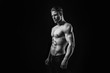 © KDdesignphoto - Black and white. Muscular model sports young man on dark background. Fashion portrait of strong brutal guy with a modern trendy hairstyle. Sexy torso. Male flexing his muscles.