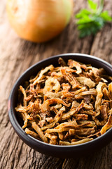 Wall Mural - Fresh homemade crispy fried onion strings in rustic bowl, raw onion in the back (Selective Focus, Focus one third into the image)