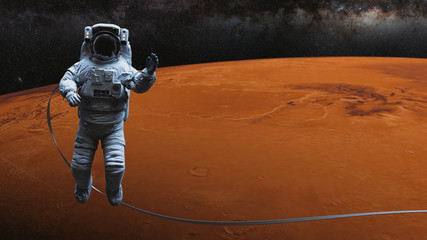 Wall Mural - astronaut waving during a space walk in orbit of planet mars