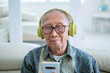 © Creativa Images - Old man enjoying music with a phone