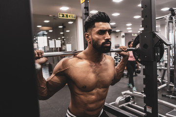 Poster - Man at the gym. Execute exercise squatting with weight, in gym