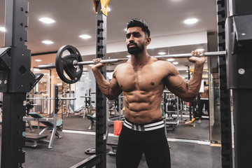 Poster - Man at the gym. Execute exercise squatting with weight, in gym